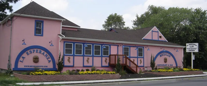 The restaurant's long pink building with blue trim, two arched signs and yellow flowers along the front, about 2006