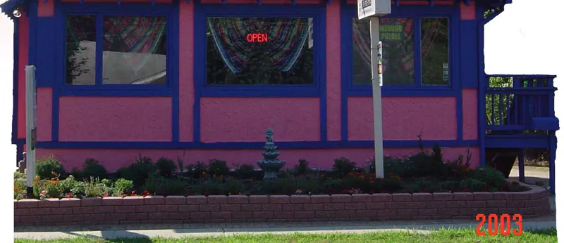 The pink and violet-blue front of the restaurant with its OPEN sign and pennant flags