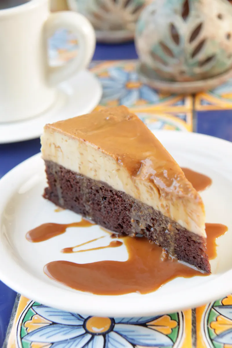 A slice of El Imposible: chocolate cake below, flan on top, caramel running onto the plate