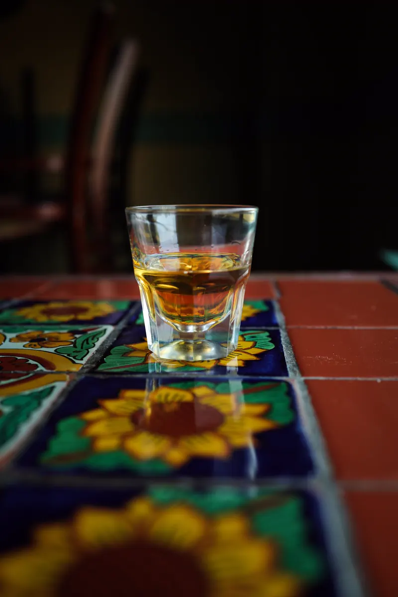 A shot of golden tequila on sunflower-pattern Talavera tiles
